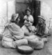 Palestine: A Palestinian woman with her two children grinding wheat, c. 1900